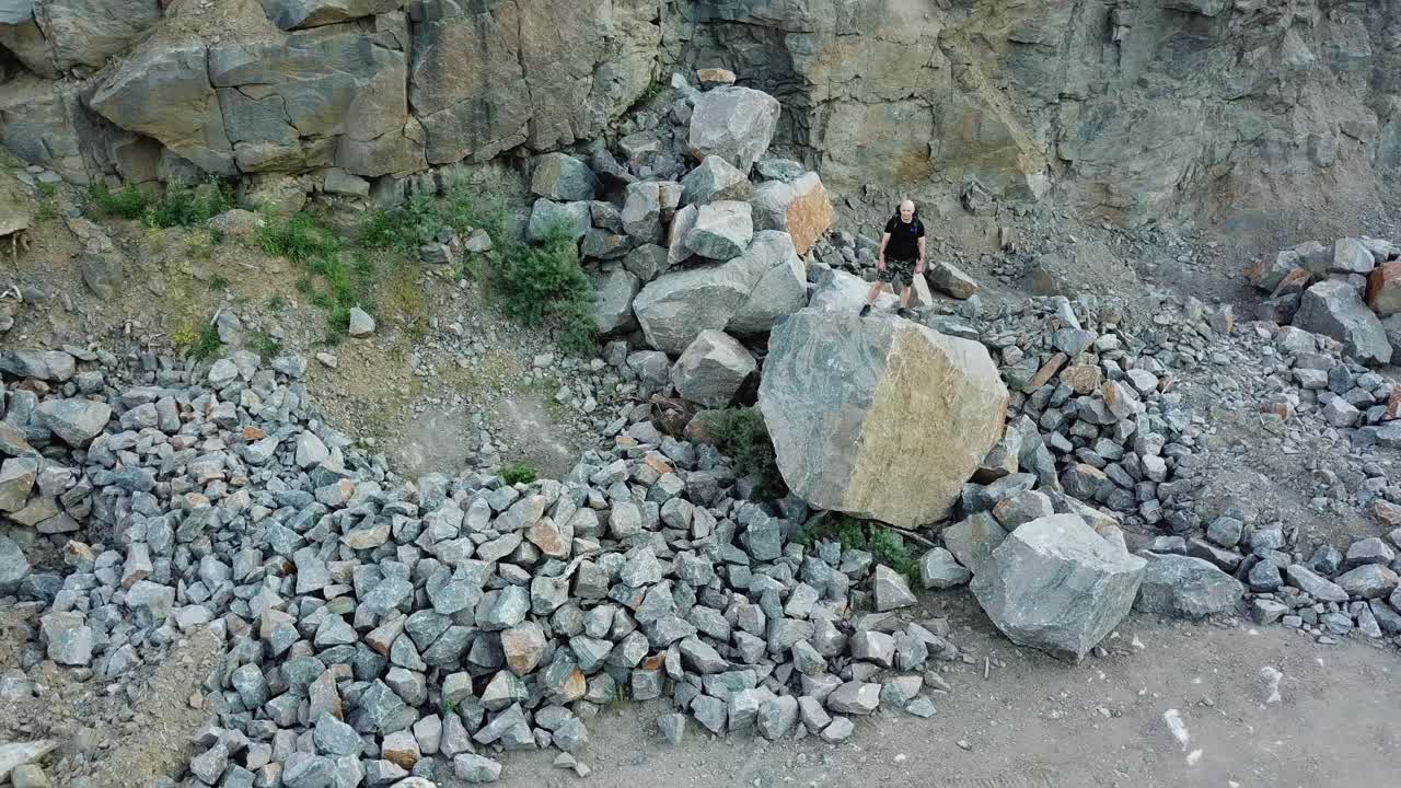 Aerial view of a young man standing on a rock. Traveler looks at the locality ahead of him. Travel concept.