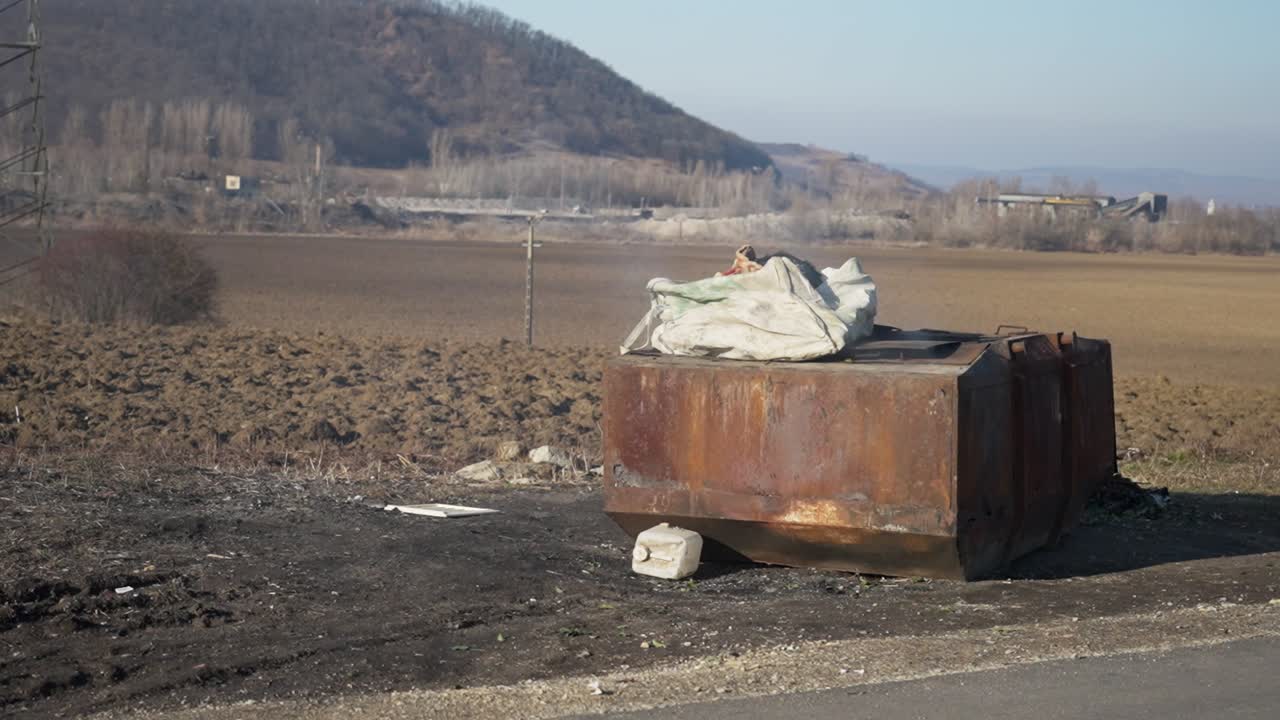 contenedor de basura oxidado en un campo rural
