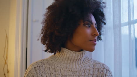 Seductive-girl-looking-window-curtain-close-up.-Curly-hair-model-staring-city