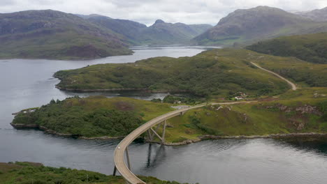 Toma-Rotatoria-De-Drones-Del-Puente-Kylesku,-Siguiendo-A-Un-Automóvil,-En-El-Noroeste-De-Escocia,-Que-Cruza-El-Lago-A&#39;cairn-Bain-En-Sutherland