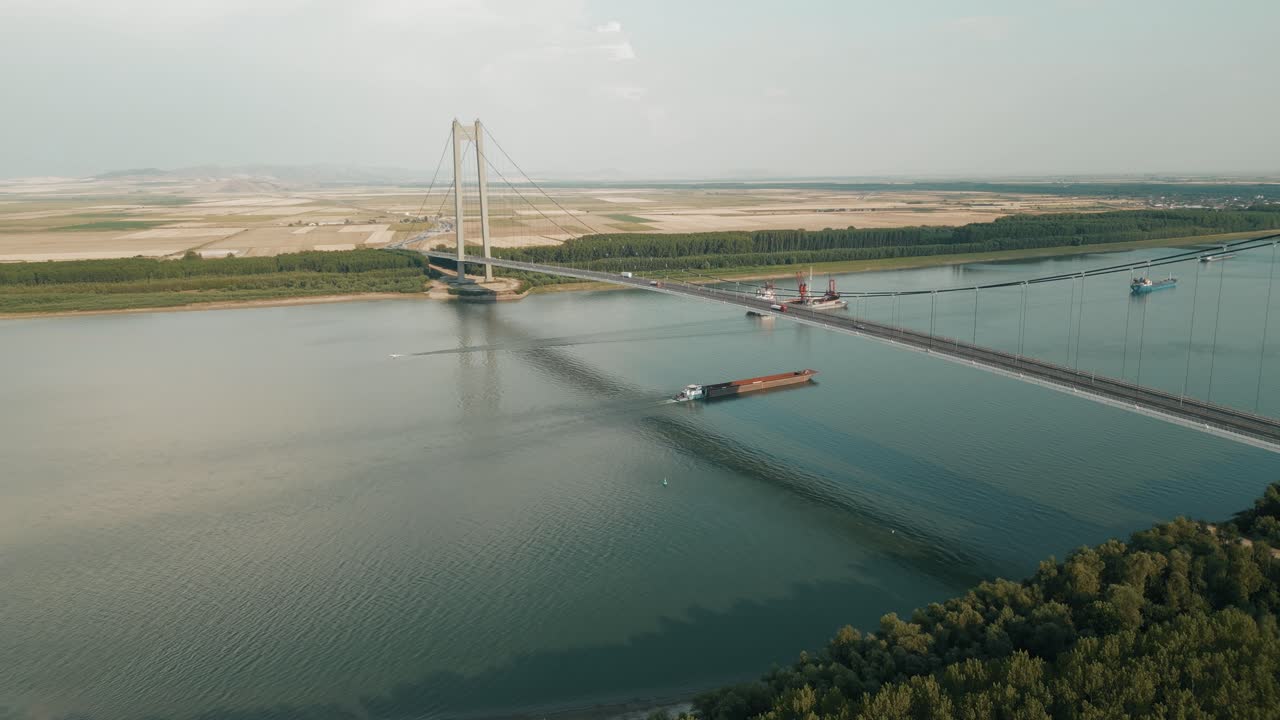 Ships Sailing Across The Danube River Under The Braila Suspension Bridge In Galati, Romania. Aerial Drone Shot