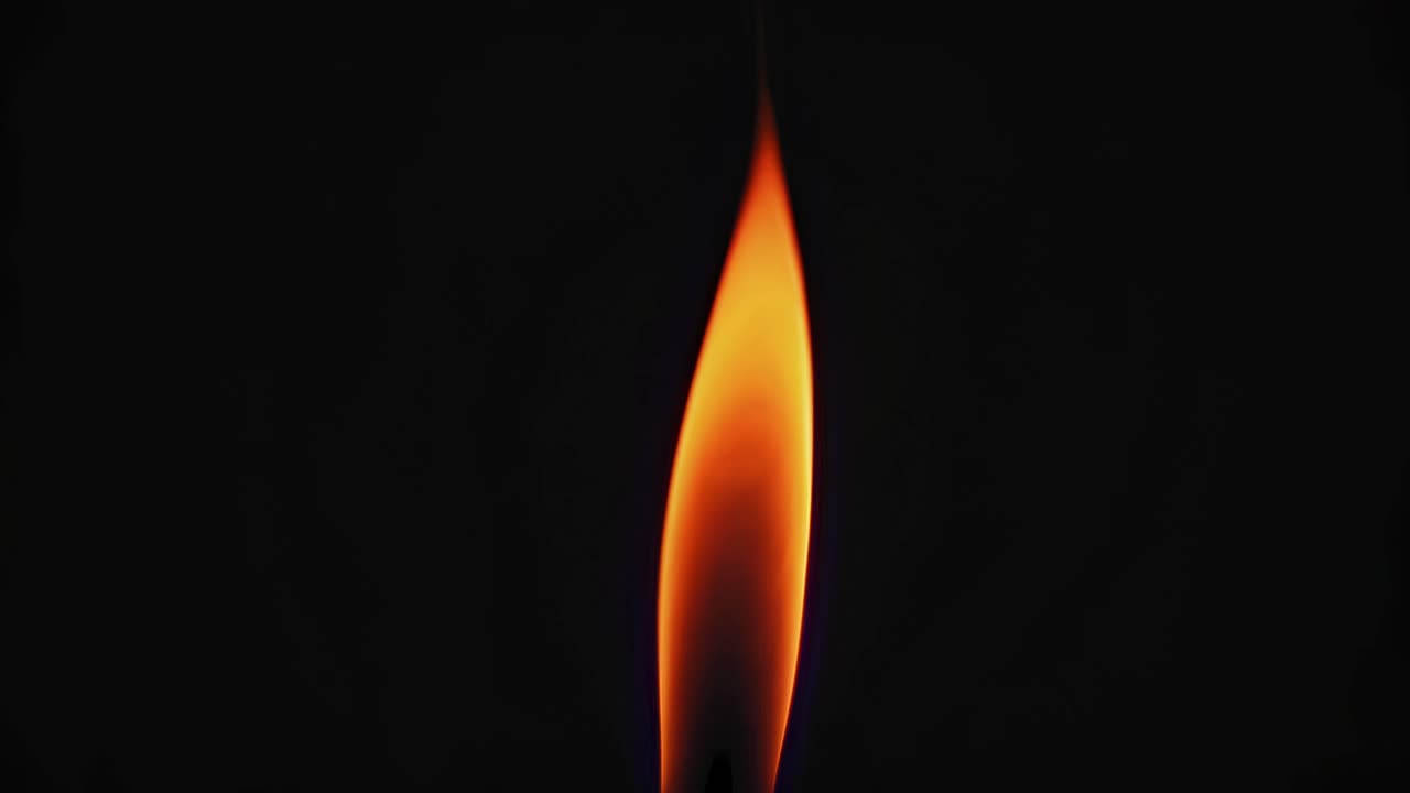Close-up of a candle flame against a dark background, shot from a side angle