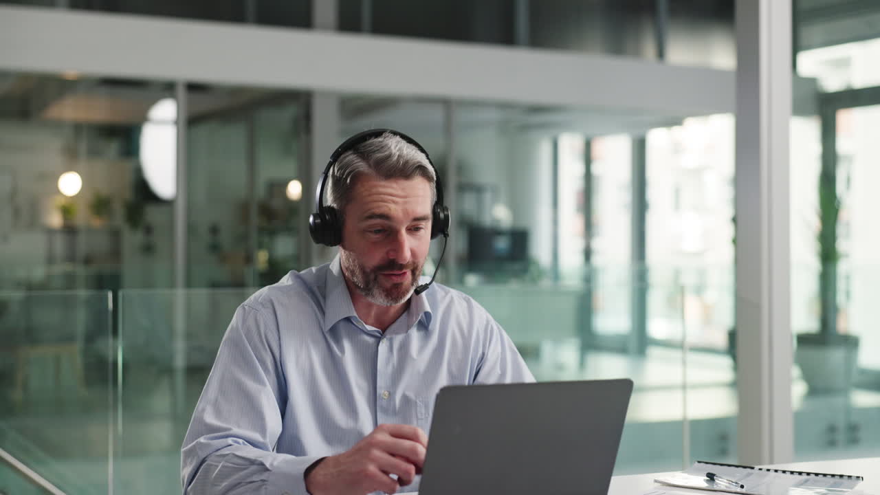Mand med headset bruger bærbar computer på kontoret