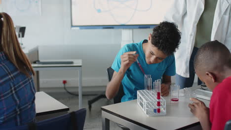 in school, boys conducting science experiment with test tubes in classroom