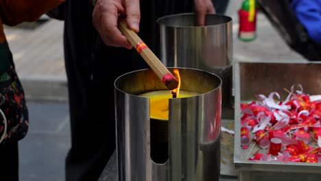 adult hands burning incense sticks with the flame of a candle