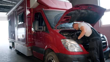 Mechanic working on a red van's engine in a garage
