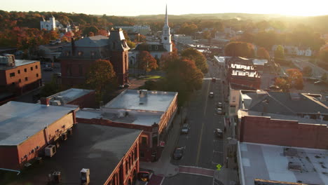 Flying-low-over-main-street-in-October-at-sunrise-in-Hudson,-Massachusetts