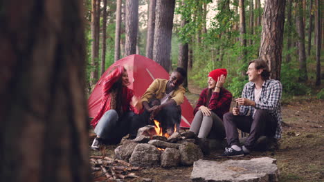 friends camping by a campfire in a forest