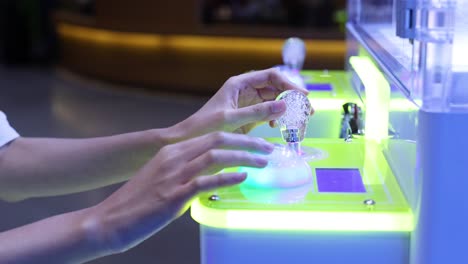 hands interacting with a glowing game machine