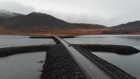 drone aerial view of car on river overpass in scenic humid landscape of iceland