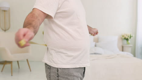 Unrecognizable-Boy-Measuring-His-Waist-In-The-Bedroom