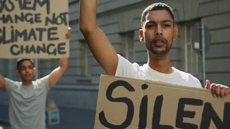 two mixed race men on a protest march holding placards raising hands and shouting