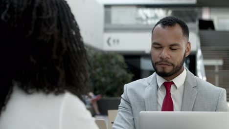 Two-cheerful-workers-sitting-at-cafe-and-talking