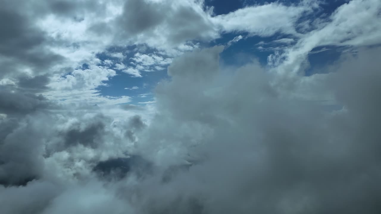 An immersive cockpit view as seen by the pilots of a jet while flying peacefully thgrough multi-layered ethereal clouds in an intense blue color sky