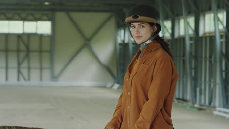 young woman in riding helmet in an indoor arena