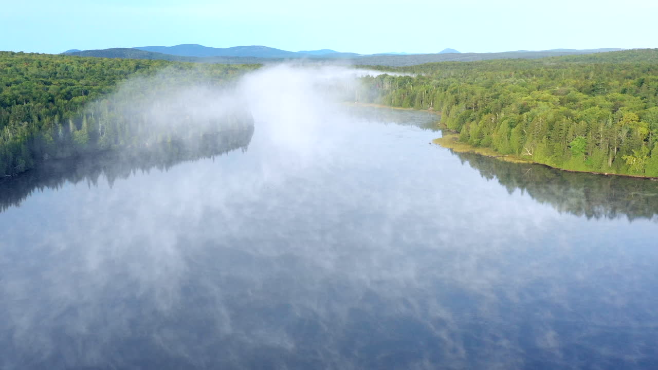 메인 광야에 있는 스펙터클 연못의 고요한 푸른 물 위에 매달려 있는 안개와 안개 위로 공중 드론 샷
