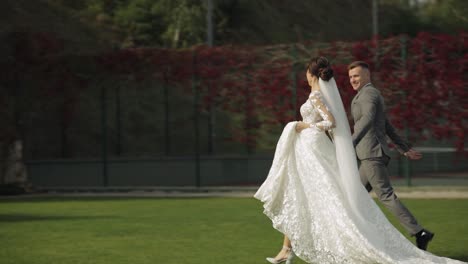 Lovely-newlyweds-caucasian-bride-groom-running-in-park,-holding-hands,-wedding-couple-family