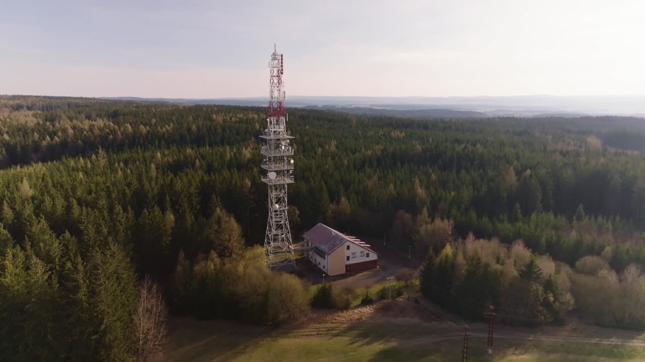 The television tower covers the signal for the surrounding villages. Forest landscape at sunset from a drone