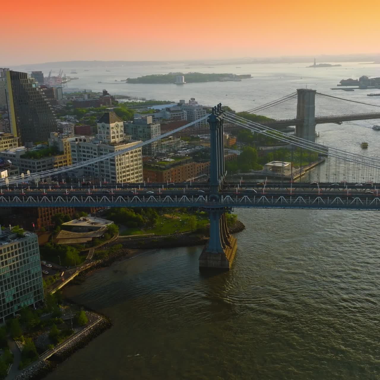 Cars moving by the Manhattan Bridge. Stunning view of the city and endless river against fantastic pink and orange sky