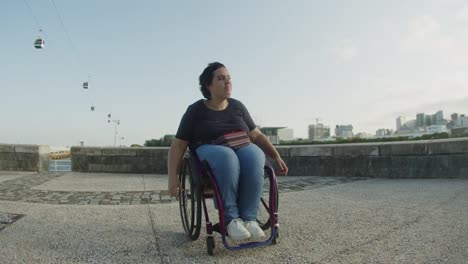 mujer alegre usando silla de ruedas bailando y conociendo a un amigo