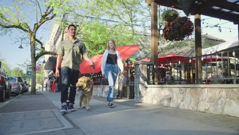 la pareja está caminando felizmente con su perro por la ciudad.