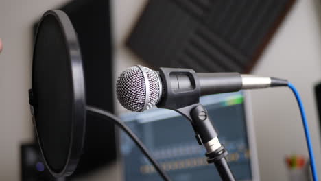 primer plano en un micrófono vocal y filtro pop con un invitado de radio hablando durante una sesión de grabación de podcast en un estudio