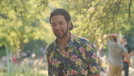 portrait of a young handsome stylish guy in a cap and hawaiian shirt smiling at the camera