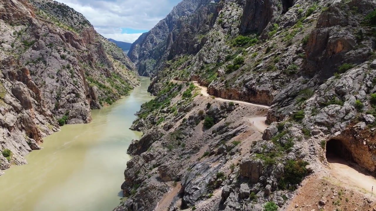 Volo di drone all'interno della profonda gola rocciosa del Canyon di Karanlik che rivela la storica strada in pietra intagliata a mano. Maestoso terreno montuoso e paesaggio selvaggio remoto in Turchia