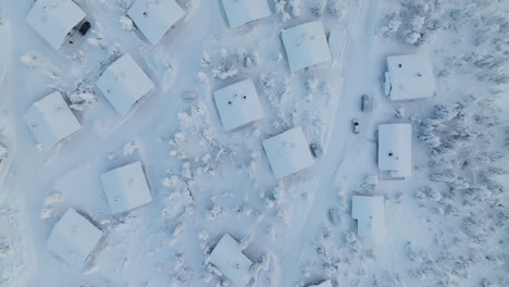 snowy cottage in mountain forest, winter in lapland - birds eye, drone shot