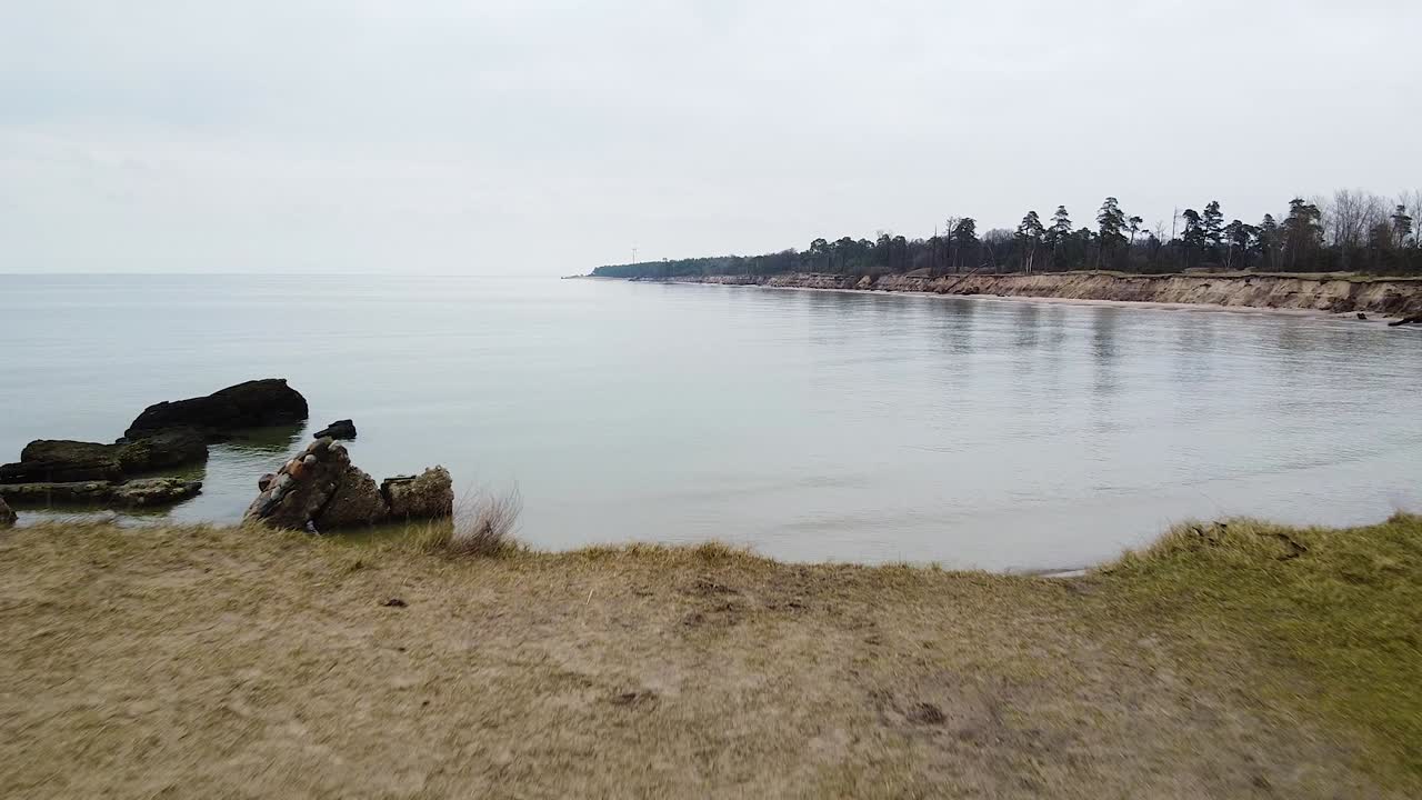 Aerial view of abandoned seaside fortification building at Karosta Northern Forts on the beach of Baltic sea in Liepaja in overcast spring day, low establishing drone shot moving backwards
