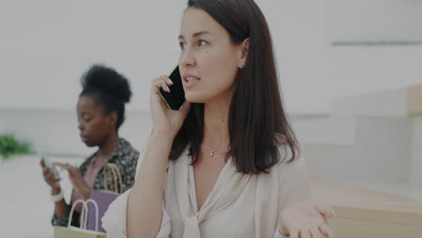 women talking on phones in a shopping mall