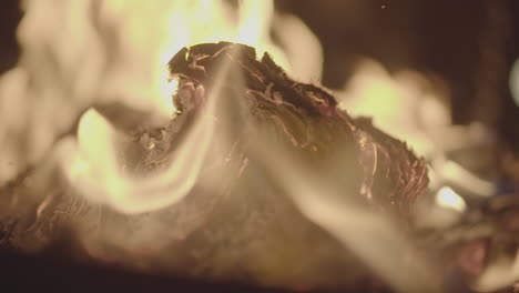 slowmotion shot of a fire and flames burning away a newspaper in a fire pit creating sparks and smoke log