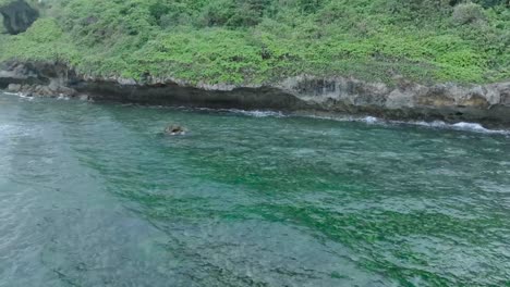 Slow-Motion-Drone-View-of-Waves-crashing-over-shallow-coral-reef-and-cliff-coastline-in-Uluwatu-Bali-Indonesia