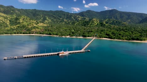 Tour-ship-docked-at-Komodo-National-Park's-Loh-Liang-pier-near-the-entrance-to-the-dragon-encounter,-Aerial-wide-orbit-left-shot