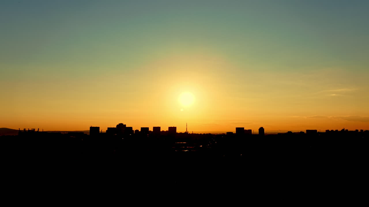 Nascer do sol sobre o horizonte da cidade, com edifícios silhuetados contra o céu ao amanhecer, nas primeiras horas da manhã, em um cenário urbano