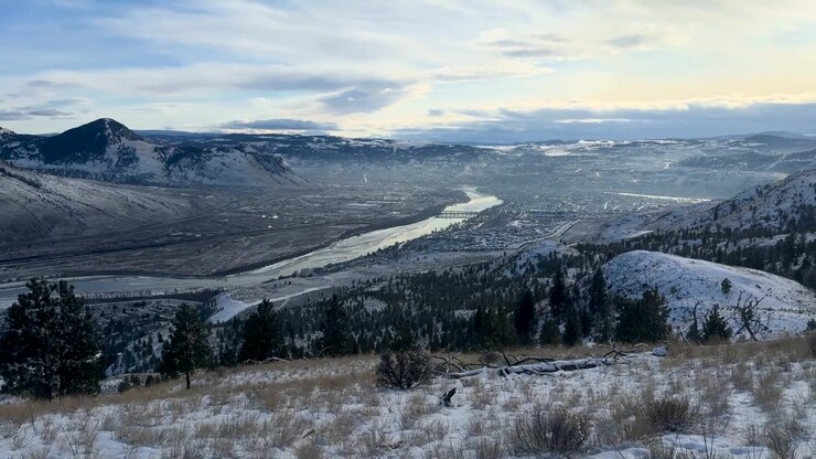 Scatto a mano libera di un paesaggio innevato panoramico con fiume e montagne a Batchelor Hill, Kamloops, inquadratura chiara, illuminazione naturale, che evoca tranquillità e vastità