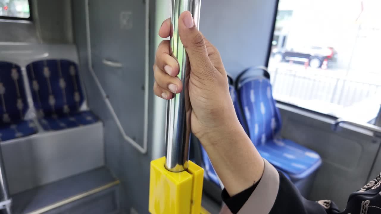 公共バスの車内でポールを握る手のクローズアップ