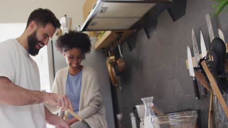 video de una feliz pareja diversa riendo y cocinando el desayuno en la cocina, con espacio para copiar