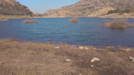 Upwards-camera-movement-from-man's-boots-over-a-water-reservoir-in-the-California-Farming-area