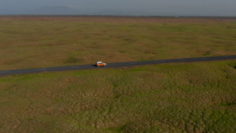 Drone-View-Coche-Deslizante-Viajando-Pacíficamente-En-La-Carretera-De-Circunvalación-En-Islandia.-Vista-Aérea-Turista-Conduciendo-Coche-Descubriendo-La-Naturaleza-En-Islandia-Con-Un-Idílico-Paisaje-Panorámico