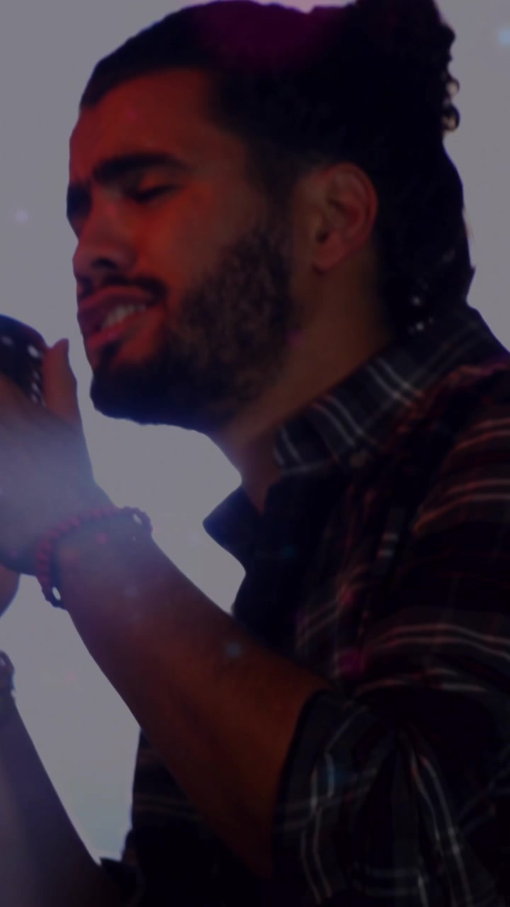 Vertical video: Man singing into retro mic, backlight flaring into haze, fading, revealing singer