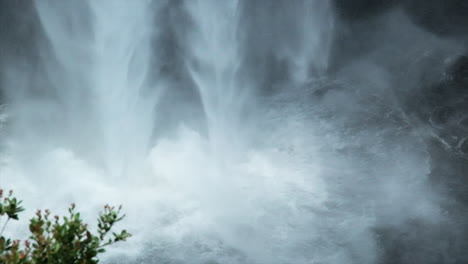 close up of akaka falls crashing into pool at base of waterfall