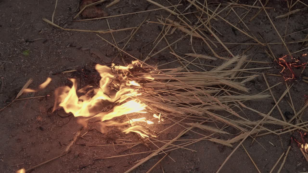 Straw catches fire on rural ground slow motion