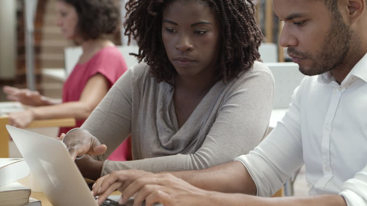 hombre y mujer afroamericanos concentrados usando laptop