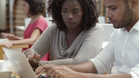 Concentrated African American man and woman using laptop