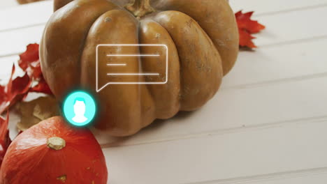 pumpkin and autumn leaves with chat bubble animation on white wooden surface