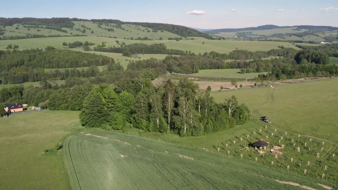 Ripresa aerea panoramica 4k rotante di un boschetto di alberi e piantine nel mezzo di campi verdi, circondato da una campagna panoramica di Dolní Morava, Repubblica Ceca