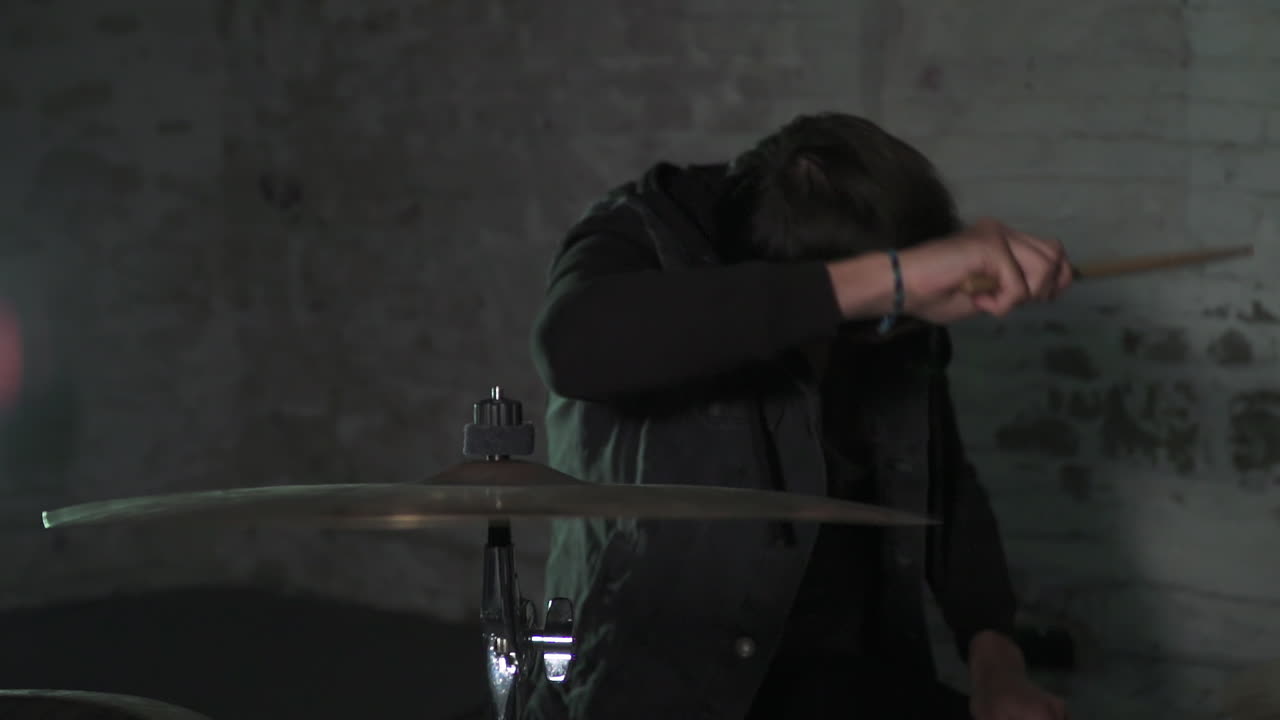 En ung europeisk vuxen slår på en cymbal på sitt trumset i slow motion