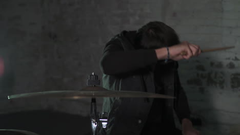 a young european adult is hitting a cymbal of his drumset hard in slow motion
