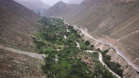 descending drone shot of a green valley and a river next to a highway in the mountains of peru